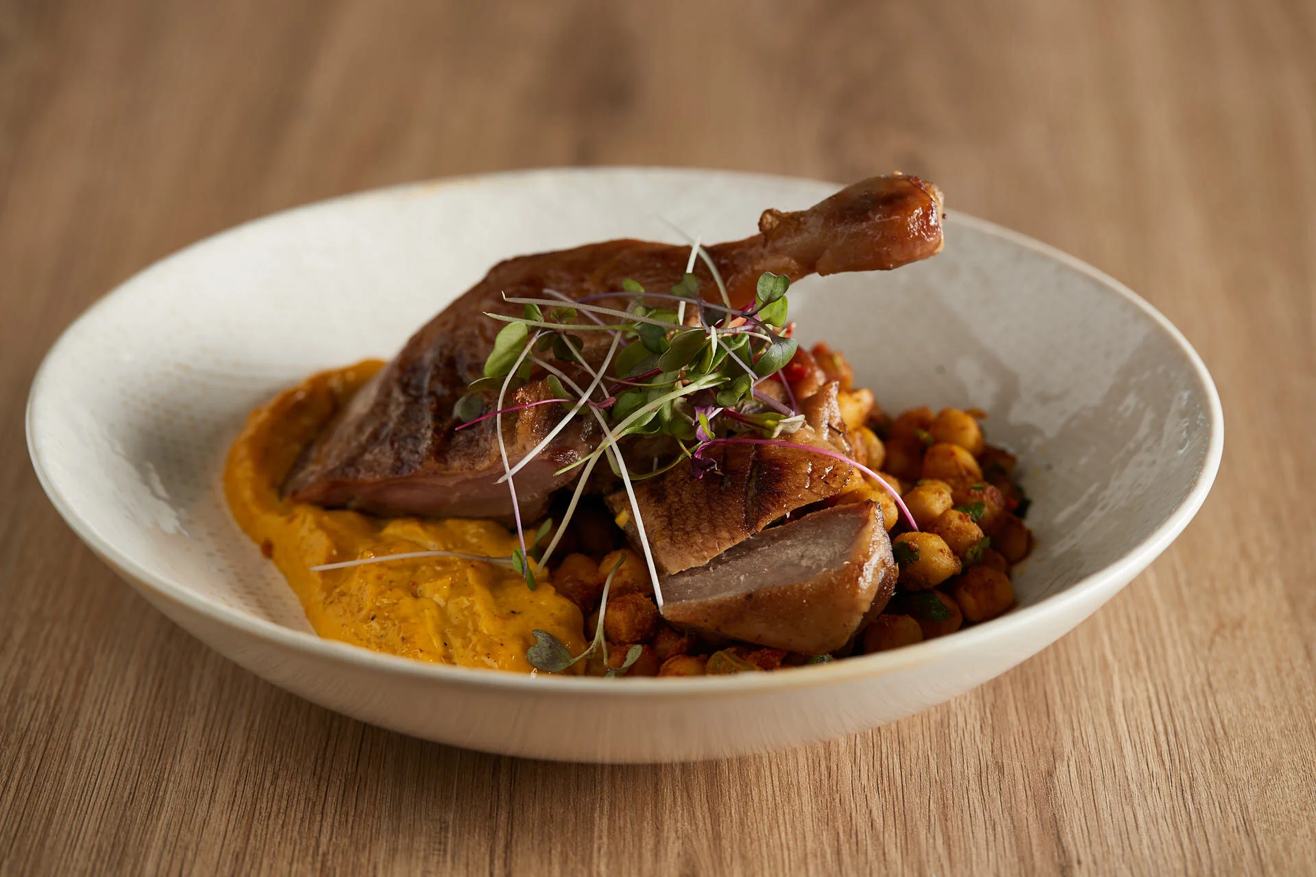 Roasted duck served with chickpeas and seasonal greens